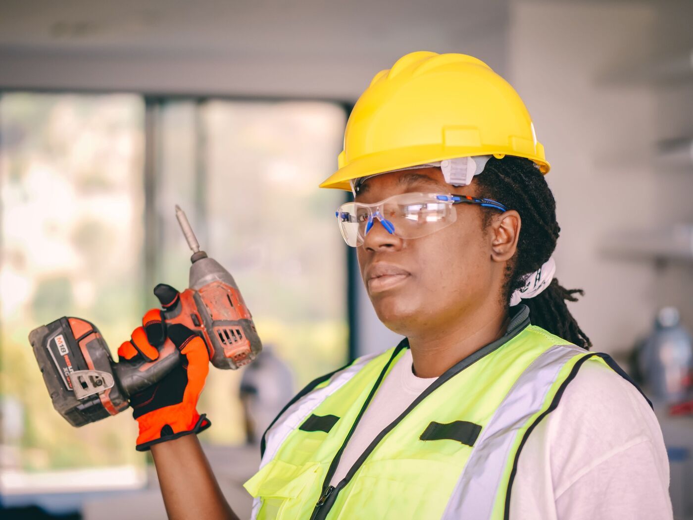 A smiling engineer holding a drill and hammer