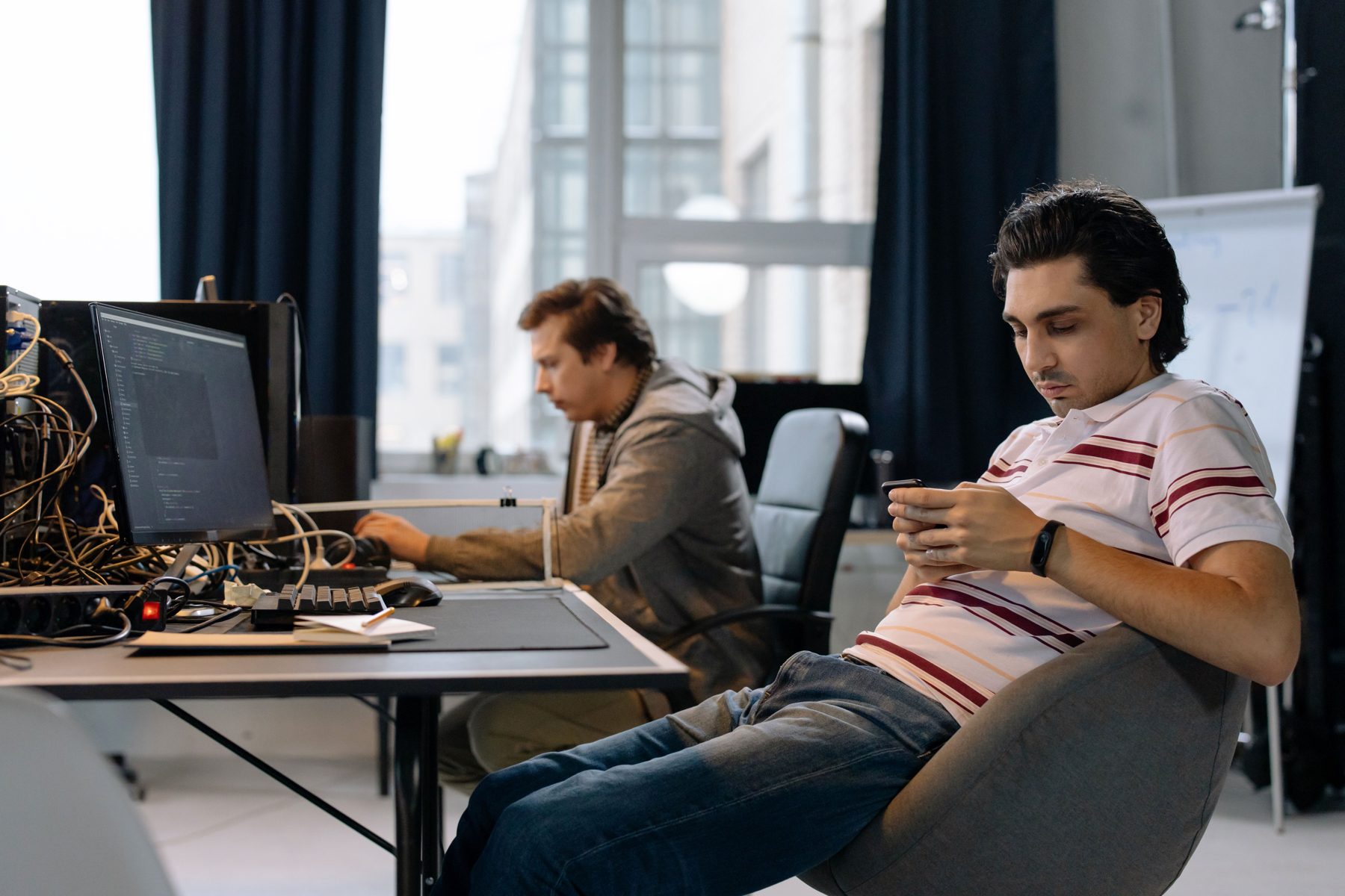 A developer relaxing at a desk and checking a phone