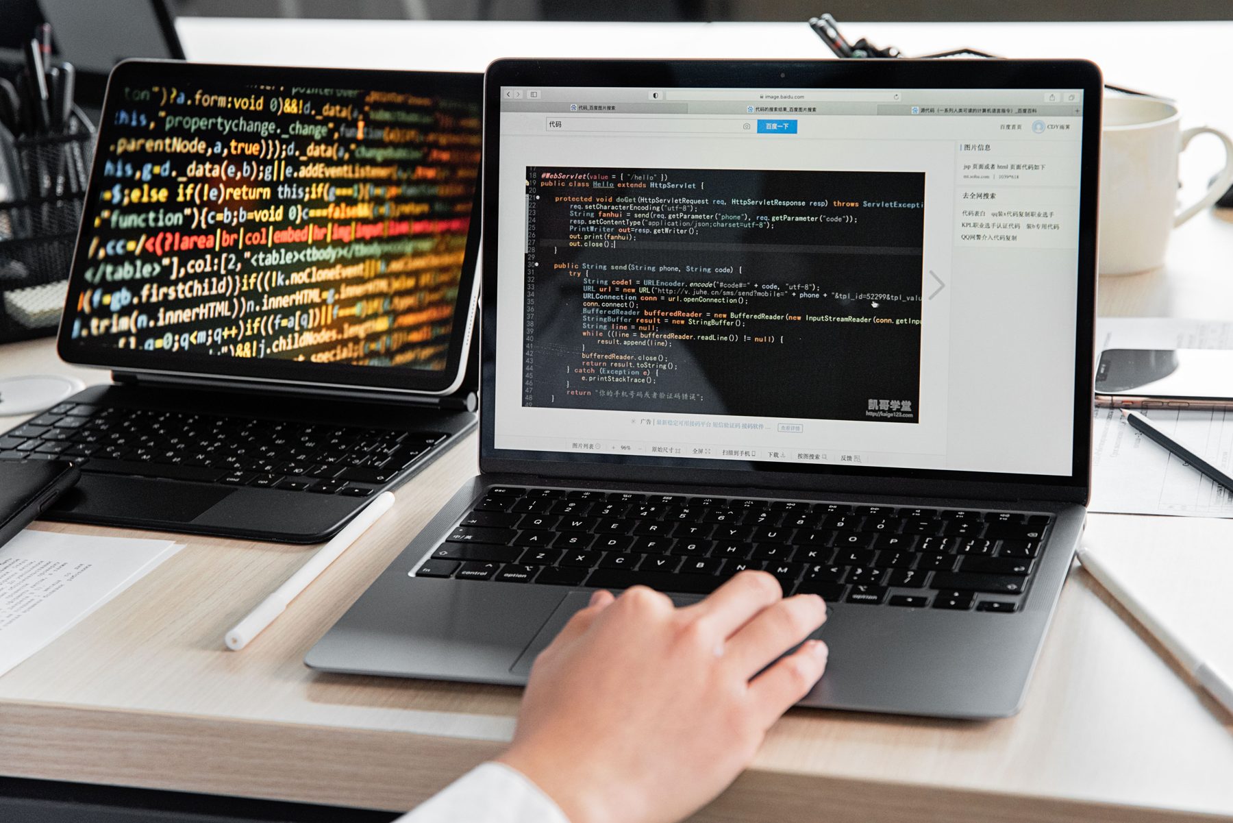 Two laptops showing code and a web page