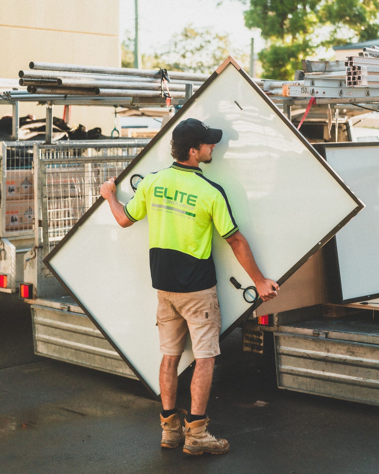 A Sunfield fitter carrying a large solar panel between two vans