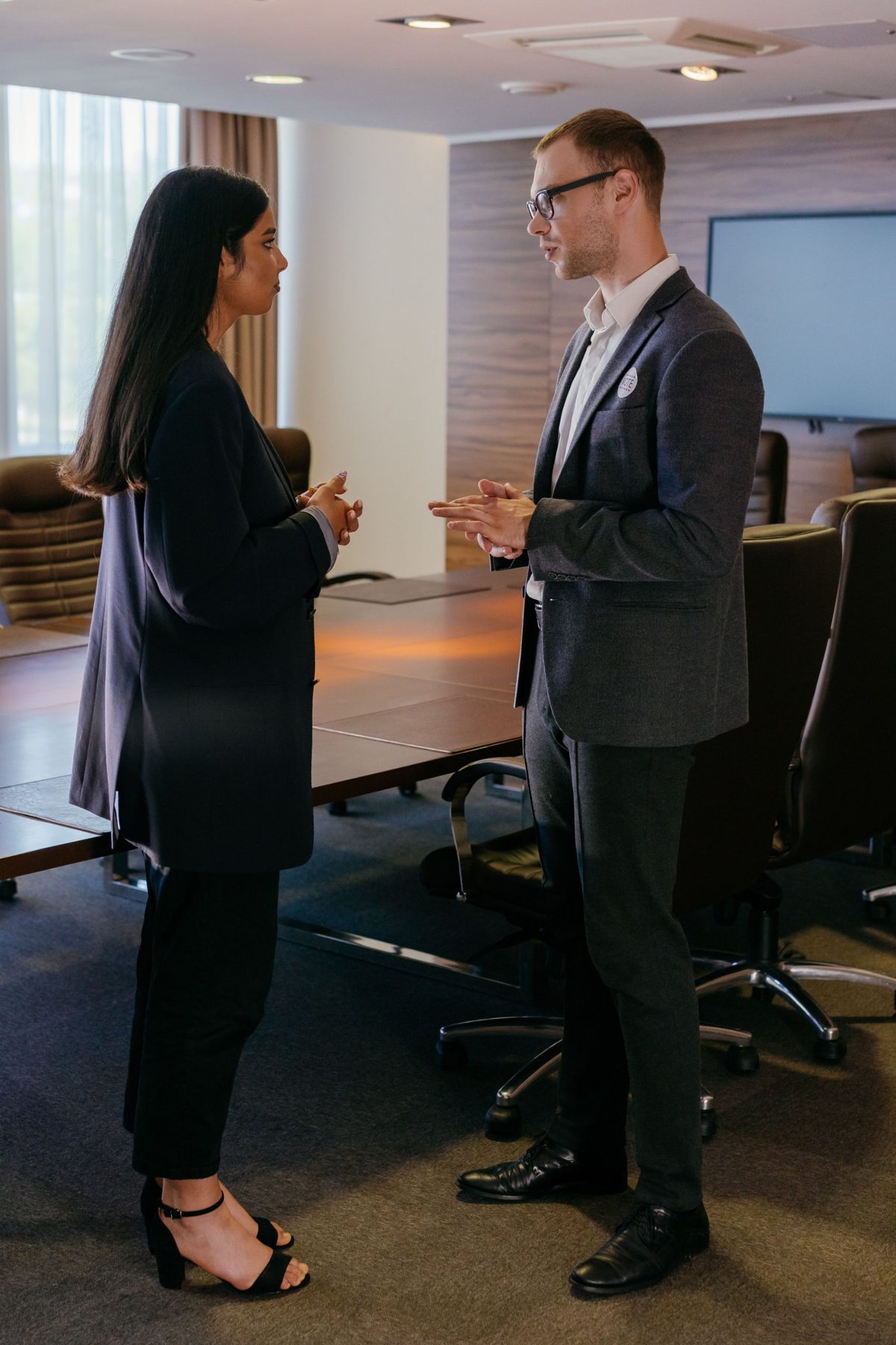 Two colleagues talking together beside a boardroom table